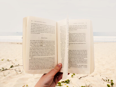 Persona lee un libro en la tranquilidad de una playa desierta