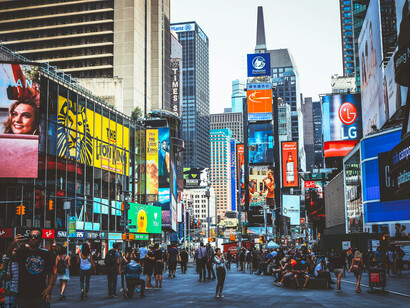 Crowds move through Times Square beneath its towering digital billboards in New York City, USA