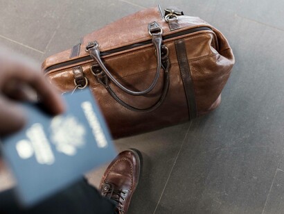 Travel bag with essentials and passport in hand