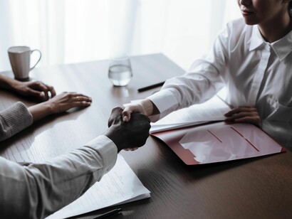 Um homem e uma mulher apertam as mãos durante um encontro profissional, com o enquadramento concentrado no gesto. A construção de uma relação de confiança é relevante para o acompanhamento social e para a articulação de estratégias de reinserção