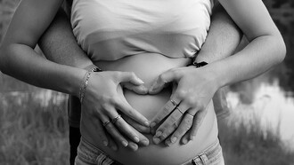 In eager anticipation, a loving man tenderly cuddles his pregnant wife, both excitedly awaiting the arrival of their baby, embracing the precious moments together
