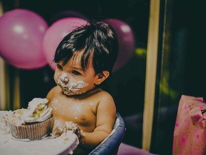 A one-year-old celebrating his milestone by shoving his face in his birthday cake