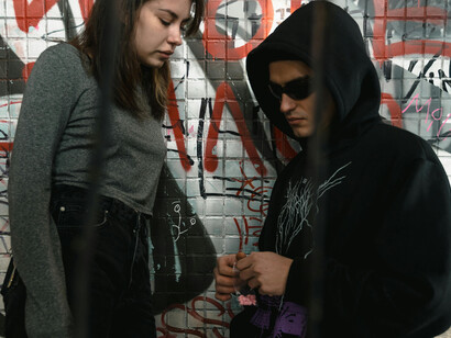 A man and a woman exchanging drugs in an abandoned, graffiti-covered building