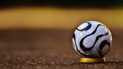 Bola de futebol posicionada em campo antes de iniciar uma partida