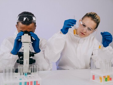 Scientists studying biological samples through a microscope, reflecting research into new approaches for understanding and treating cancer