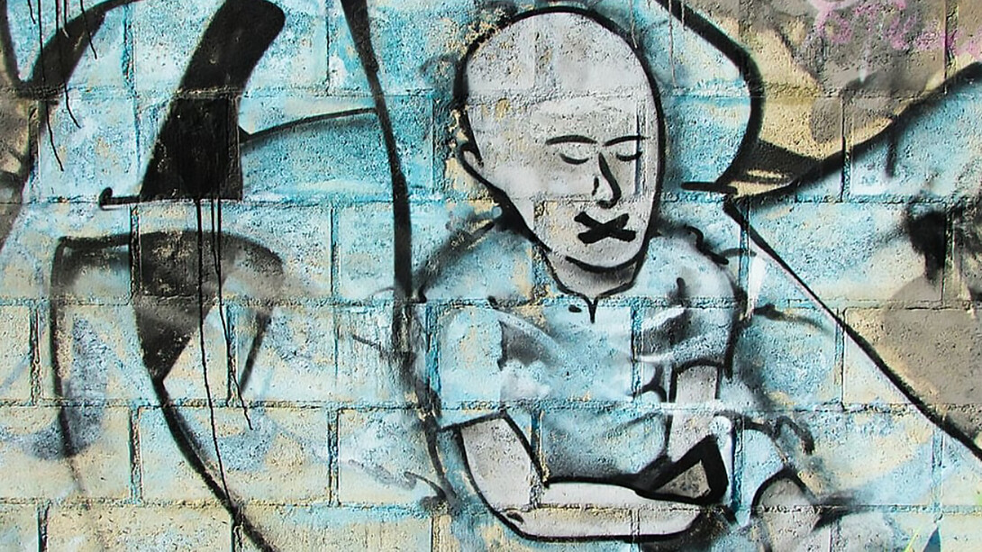 A man painted in blue graffiti, symbolizing censorship, silence, and the emotional toll of cancel culture and social oppression