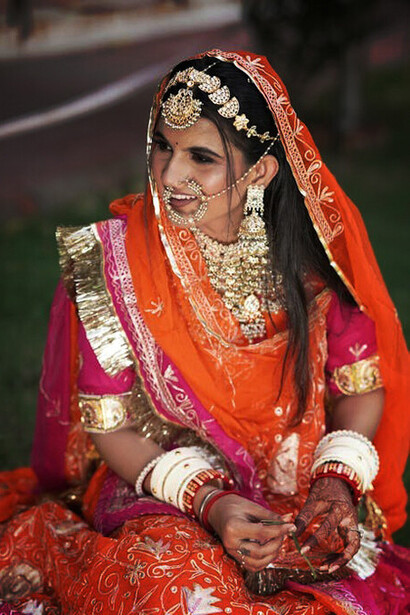 A Kumaon bride in stunning red garments and intricate golden bracelets, embracing the rich heritage of Indian weddings