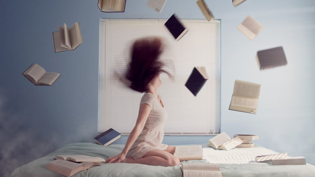 Woman sitting on bed with flying books
