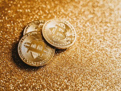 Three bitcoins on a gold background. The value of investments can increase over time