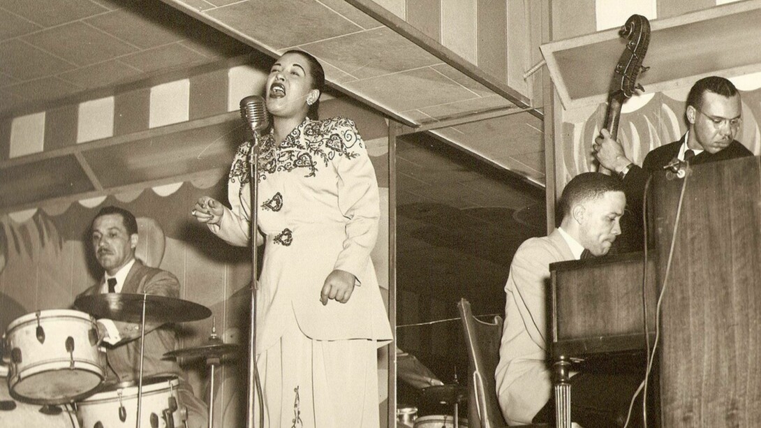 Billie Holiday performs live at Club Bali in Washington, D.C. (September 1948) alongside Al Dunn and Bobby Tucker—capturing the powerful, immediate stage presence that audiences celebrated while often disconnecting her music from the ongoing struggles of her daily life