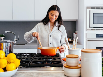 A woman's joyful smile illuminates the kitchen as she passionately prepares a meal
