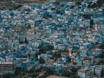 Chefchaouen’s distinctive blue-painted houses across the mountainside, representing the historical continuity of Moroccan urban life