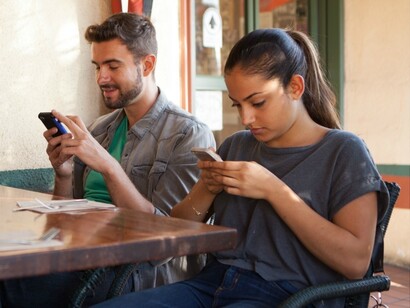 Dos jóvenes con sus móviles en un bar