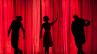 A silhouette of three performers on stage, captured in mid-action, highlights the energy and creativity of an improv performance