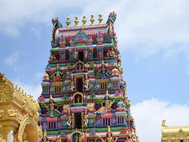 A vibrant Dravidian-style temple gopuram set against a clear blue sky in Chennai, India