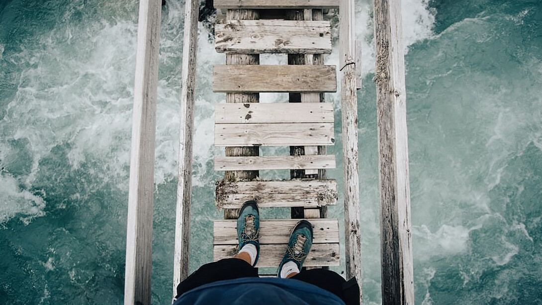 An individual standing upon a rustic wooden bridge
