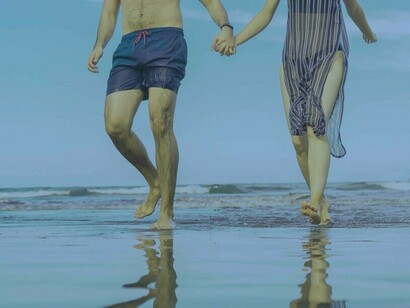 Una coppia passeggia mano nella mano lungo la spiaggia