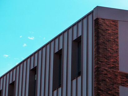 The stunning play of light and shadow on this metal-clad building highlights the dynamic aesthetic potential of metal panels, transforming the architectural landscape with their modern flair
