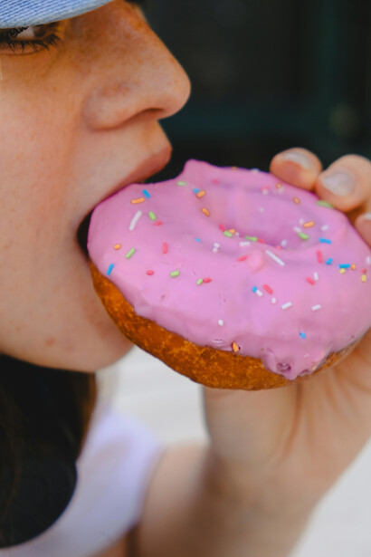 Close-up image of a woman indulging in a donut—capturing the craving, sugar rush, and addictive nature of junk food