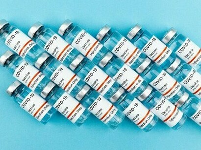 Several COVID-19 vaccine bottles resting side by side, symbolising the tension between scientific progress and societal fear