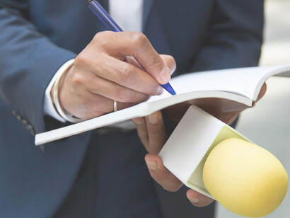 Journalist taking notes while holding a microphone during an interview