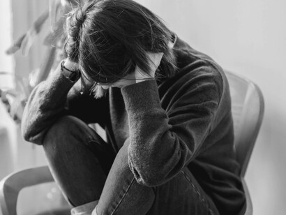 A woman burying her face in her hands as deals with her recent failure