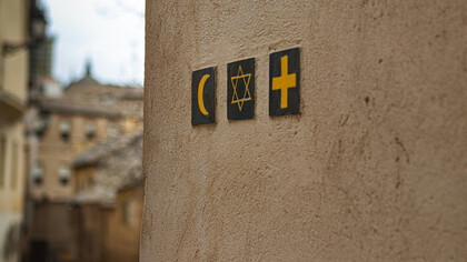 Symbols of Islam, Judaism and Christianity embedded on a wall at a street corner