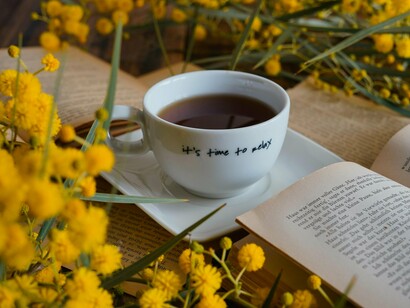 A cup of tea with the message "it's time to relax" surrounded by books and flowers, representing the value of intentional breaks from digital demands