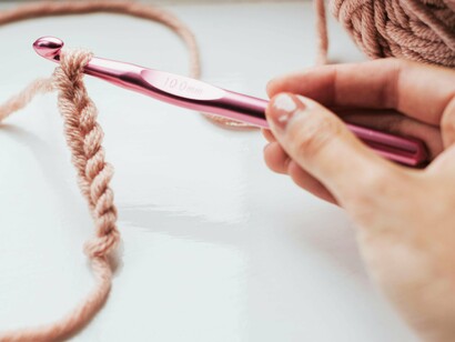 Mulher faz crochê. Como um fio invisível, o feminino está entrelaçado e não se perde de sua essência nas turbulências externas de sobrevivência