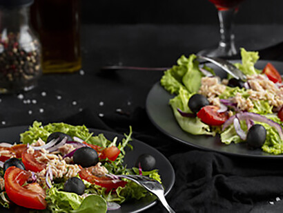 Dark plate with a fresh Mediterranean salad, topped with omega-3 rich salmon and crunchy walnuts