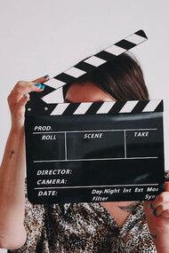 A woman holding a clapper over her face