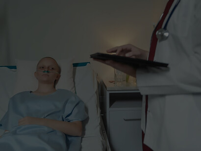 In the hushed atmosphere of a hospital room, a woman, bravely confronting cancer, lies in bed wearing a hospital gown as she undergoes the rigors of chemotherapy. Her silent fortitude speaks volumes about the resilience that defines her journey