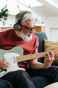 Senior man enjoying music while playing an electric guitar