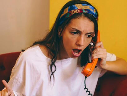 Uma jovem mulher demonstra frustração enquanto fala ao telefone. Do outro lado da linha, porém, há sempre alguém que recebe não apenas a reclamação, mas também as emoções e os julgamentos de quem liga