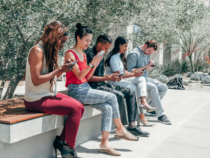 Group of friends using smartphones together outdoors