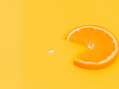 Set against a lively yellow and orange canvas, a tantalizing slice of orange and lemon shares the stage with an assortment of pills and vitamins