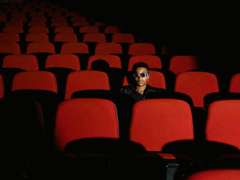 A man sitting inside the theater wearing sunglasses