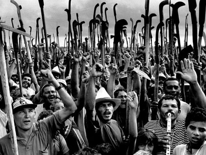 Trabalhadores reunidos, com ferramentas erguidas, em uma imagem de forte impacto visual produzida por Sebastião Salgado. Ao registrar o trabalho e as condições de vida de pessoas em diferentes partes do mundo, o fotógrafo construiu uma obra documental que dá visibilidade a trabalhadores frequentemente ausentes das narrativas dominantes