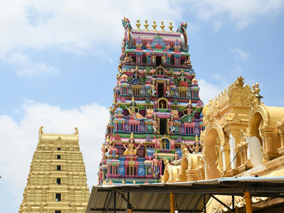 Dravidian temple gopuram in bright colors, standing tall under the blue sky in Chennai, India