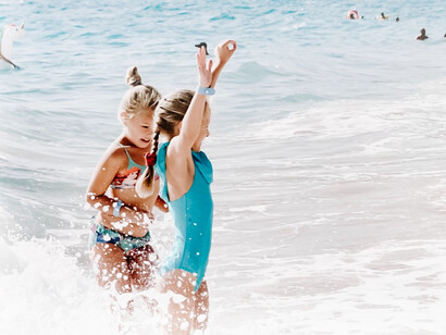 Two girls at the beach, being in a clean physical environment without pollutants is good for aging well