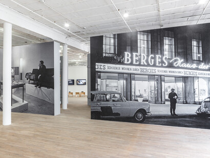 Installation view from Living with Pop. A Reproduction of Capitalist Realism, Artists Space, 2014. Left: Leben mit Pop - Eine Demonstration für den kapitalistischen Realismus, 1963 (Living with Pop – A Demonstration for Capitalist Realism) © 2014 Artists Rights Society (ARS), New York / VG Bild-Kunst, Bonn. Photo: Reiner Ruthenbeck. Inkjet print on vinyl mounted to wall Right: Exterior view of the furniture store Möbelhaus Berges Flingerstraße 11, Düsseldorf. Courtesy Archiv künstlerischer Fotografie der rheinischen Kunstszene (AFORK) © 2014 Artists Rights Society (ARS), New York / VG Bild-Kunst, Bonn. Photo: Reiner Ruthenbeck. Inkjet print on vinyl mounted to wall
