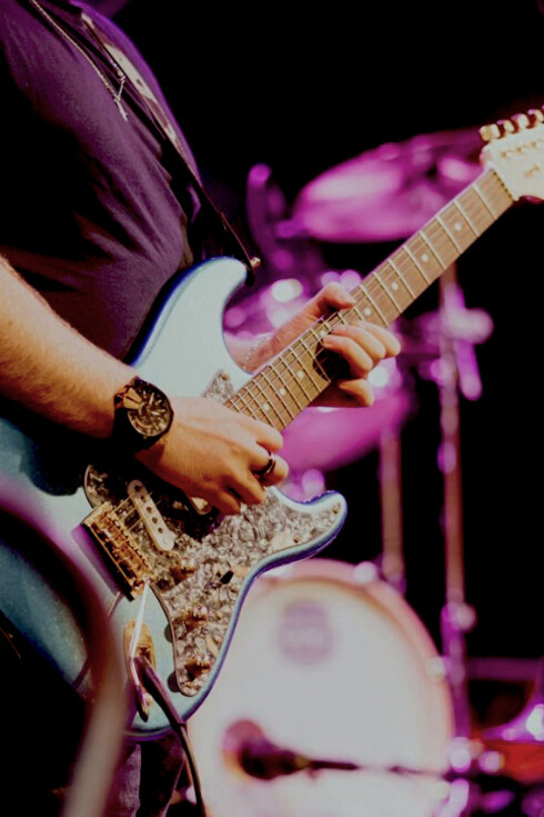 A man playing guitar on stage during a live rock concert