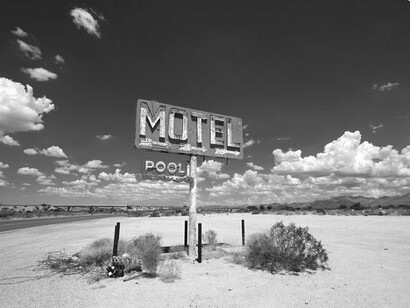 A weathered sign in the desert—offering rest, but echoing the deeper human search for place and purpose