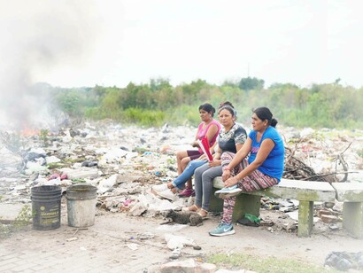 Four women sit on a bench where garbage is tossed, near their homes in Tucuman, Argentina, South America