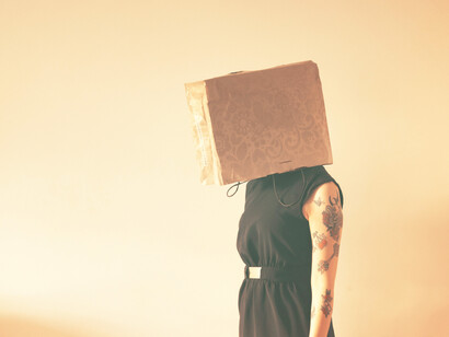 Mujer con una bolsa en la cabeza como símbolo del consumismo que nos ciega. Debemos experimentar sin miedo, lo nuevo, lo diferente, los cambios y las nuevas realidades