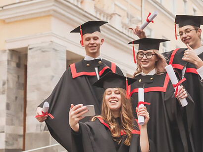 Joyful new graduates capturing memories with selfies, celebrating their academic achievements on the university campus