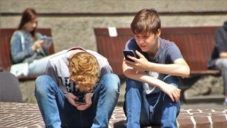 Alunos adolescentes de uma escola usam o celular durante o intervalo