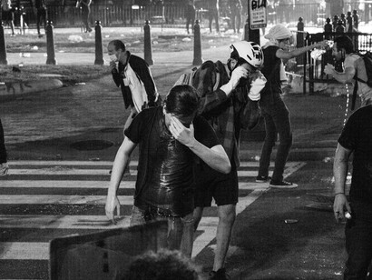 Protesters shield themselves from the thick cloud of tear gas during a tense demonstration