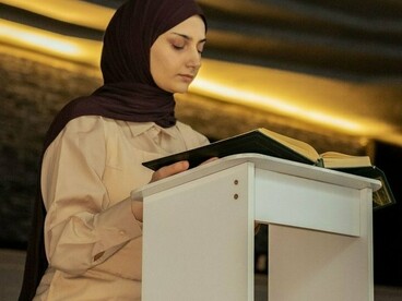 A young woman immersed in reading the Quran, representing the pursuit of Islamic knowledge and spiritual devotion