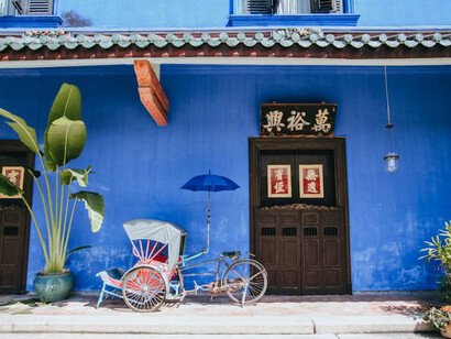 A bike and plant positioned in front of a vibrant blue wall in George Town, Penang, Malaysia, create a beautiful and lively scene
